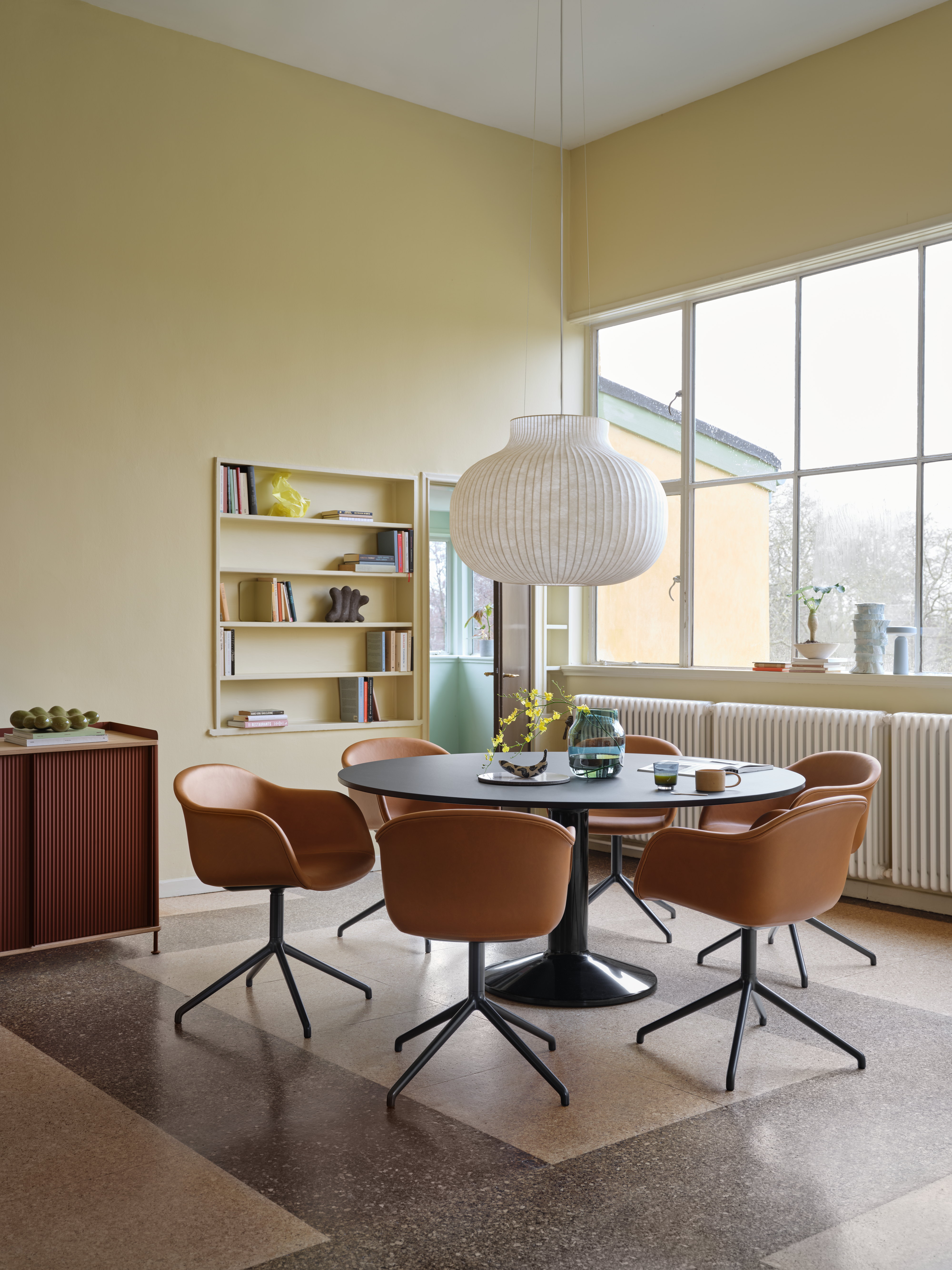 Midst Table Ø160 cm in Black - Fiber Armchair Swivel Base in Refine Leather Cognac/Black - Silent Vase Ø20 cm in Dark Green - Enfold Sideboard 148x45 H85 cm in Oak/Deep Red, Strand Pendant Lamp Ø80 cm in White - Raise Glass in Dark Blue - Ease Portable Lamp in Light Blue