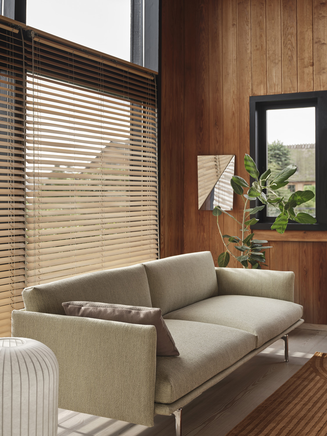 Muuto Outline Sofa, styled with a gaze mirror and Strand table lamp H59. Offers a cozy, sophisticated ambiance for any living room.