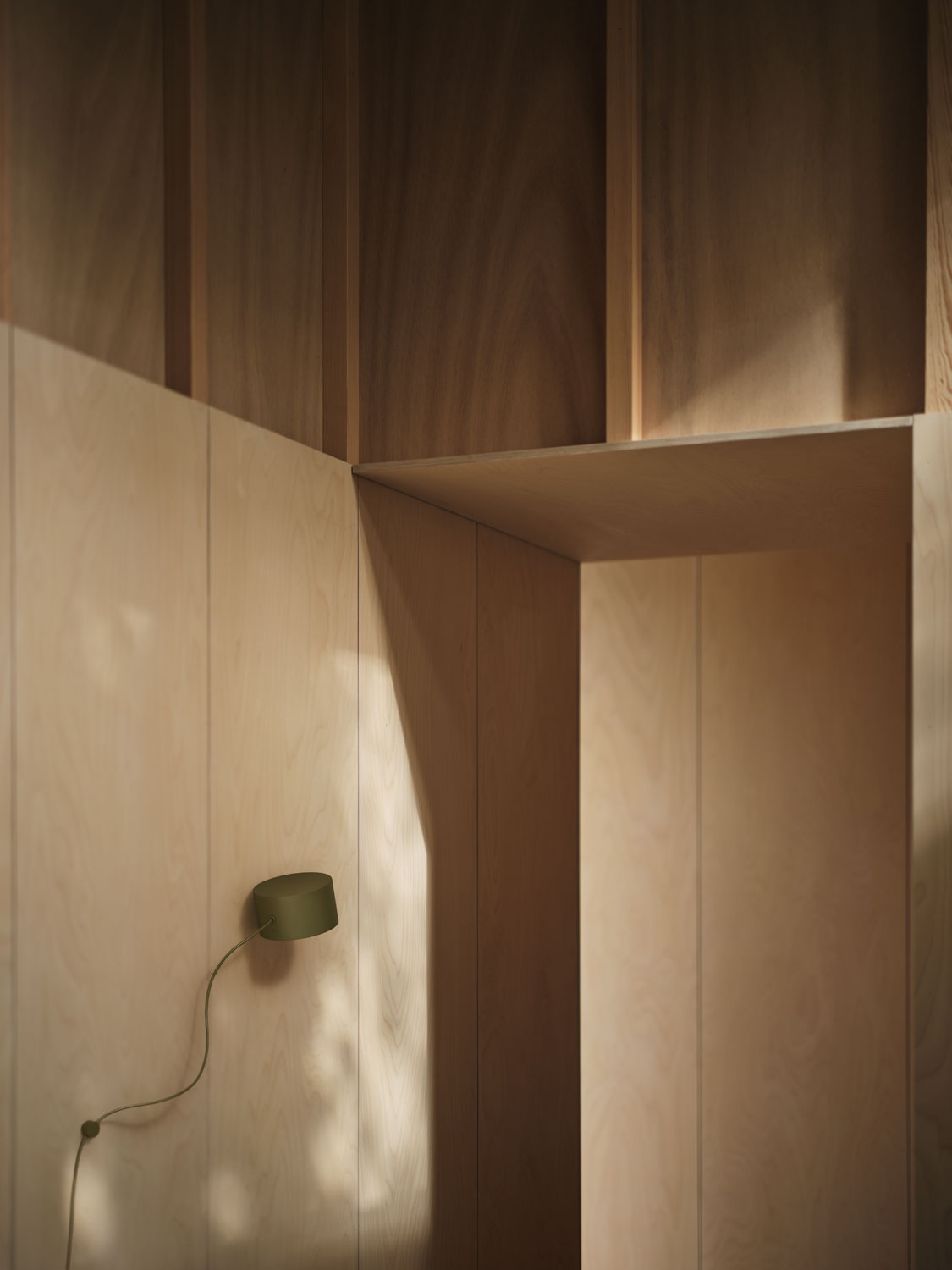 A Muuto Post wall lamp in brown green, showcasing a minimalist, modern design with a flexible, modular structure. The combination of earthy tones and functionality makes this lamp a stylish  lighting solution for any space.