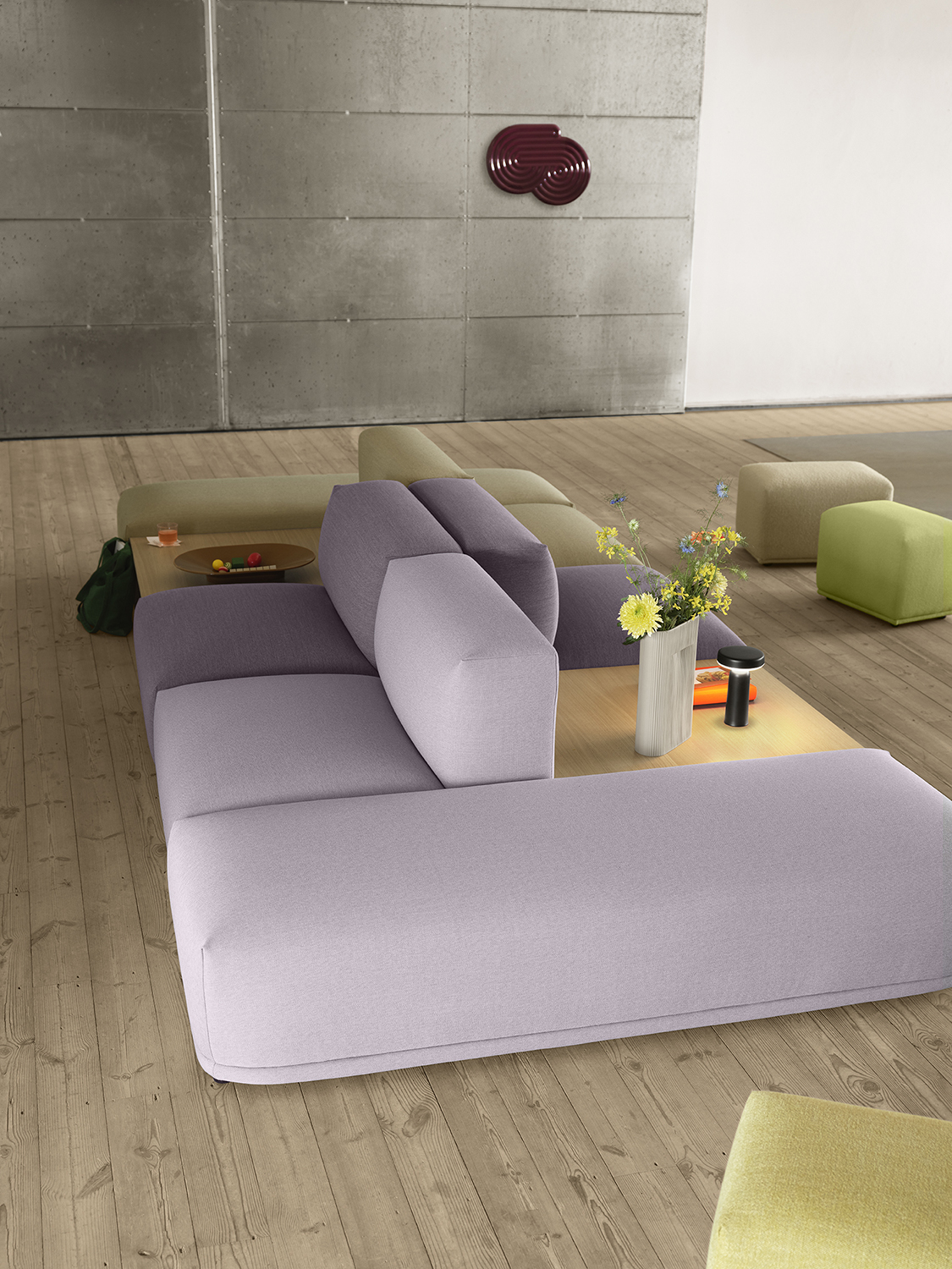 Connect Sofa in a light purple color in a spacious, minimalistic room with white and grey walls, accented by three glass pendant lights hanging above.