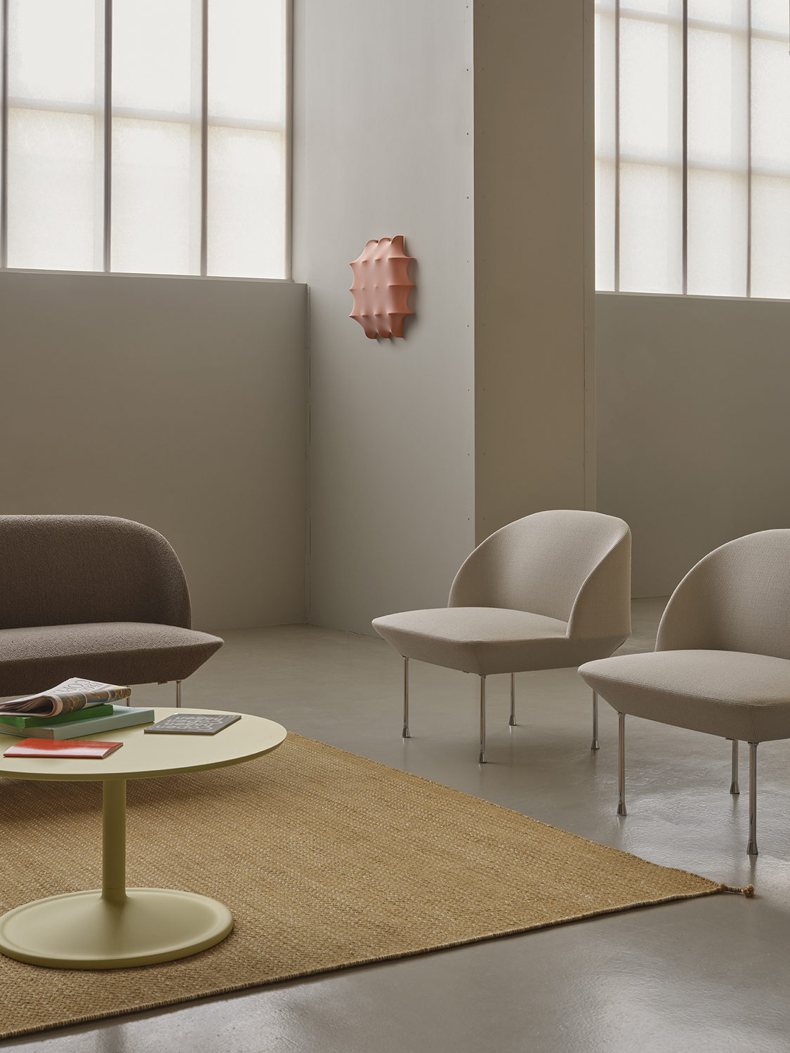 Oslo 3-seater sofa in light brown-grey, positioned next to a simple, minimalistic black floor lamp and two light grey lounge chairs.