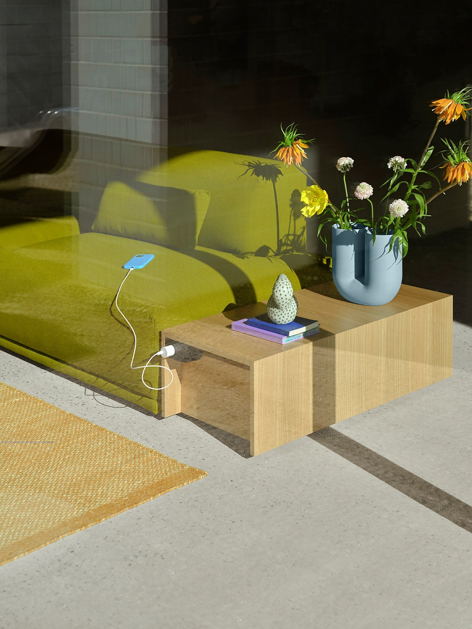 A Connect table in Oak Veneer and Connect Sofa placed in the sunlight and styled with a Kink Vase in light blue with orange and yellow flowers.  A Connect table in Oak Veneer and Connect Sofa placed in the sunlight and styled with a Kink Vase in light blue with orange and yellow flowers.