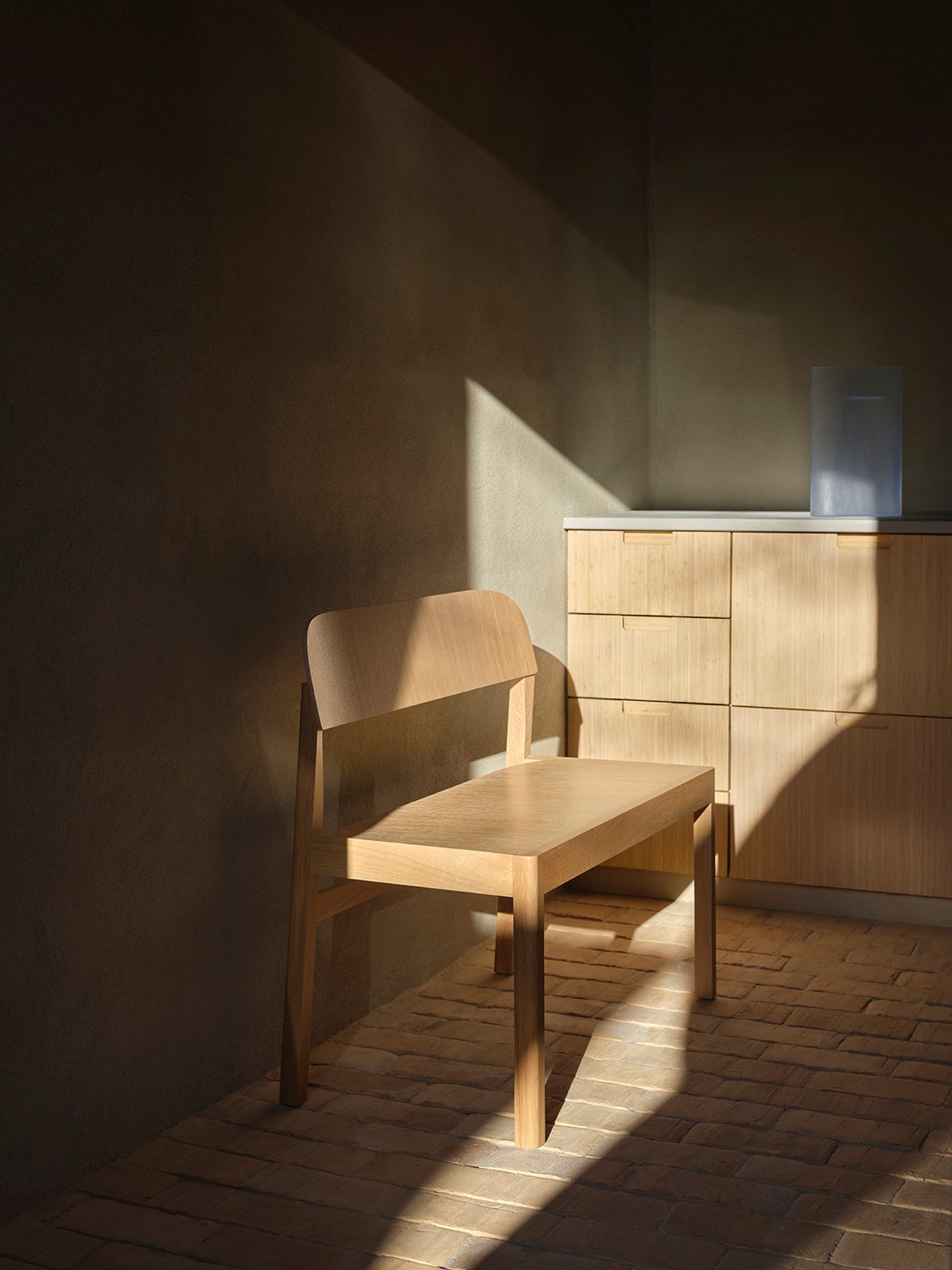 A close-up of a minimalistic modern wooden bench positioned on a rug, with sunlight casting soft shadows across the scene. A close-up of a minimalistic modern wooden bench positioned on a rug, with sunlight casting soft shadows across the scene.