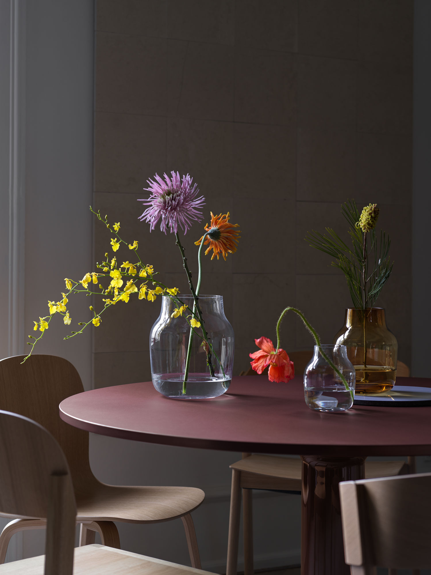 Silent Vase Ø15 cm in Burnt Orange, Ø20 & Ø11 cm in Clear - Midst Table Ø120 cm in Dark Red - Visu Chair in Oak - Workshop Chair in Oak - Cover Side Chair in Oak