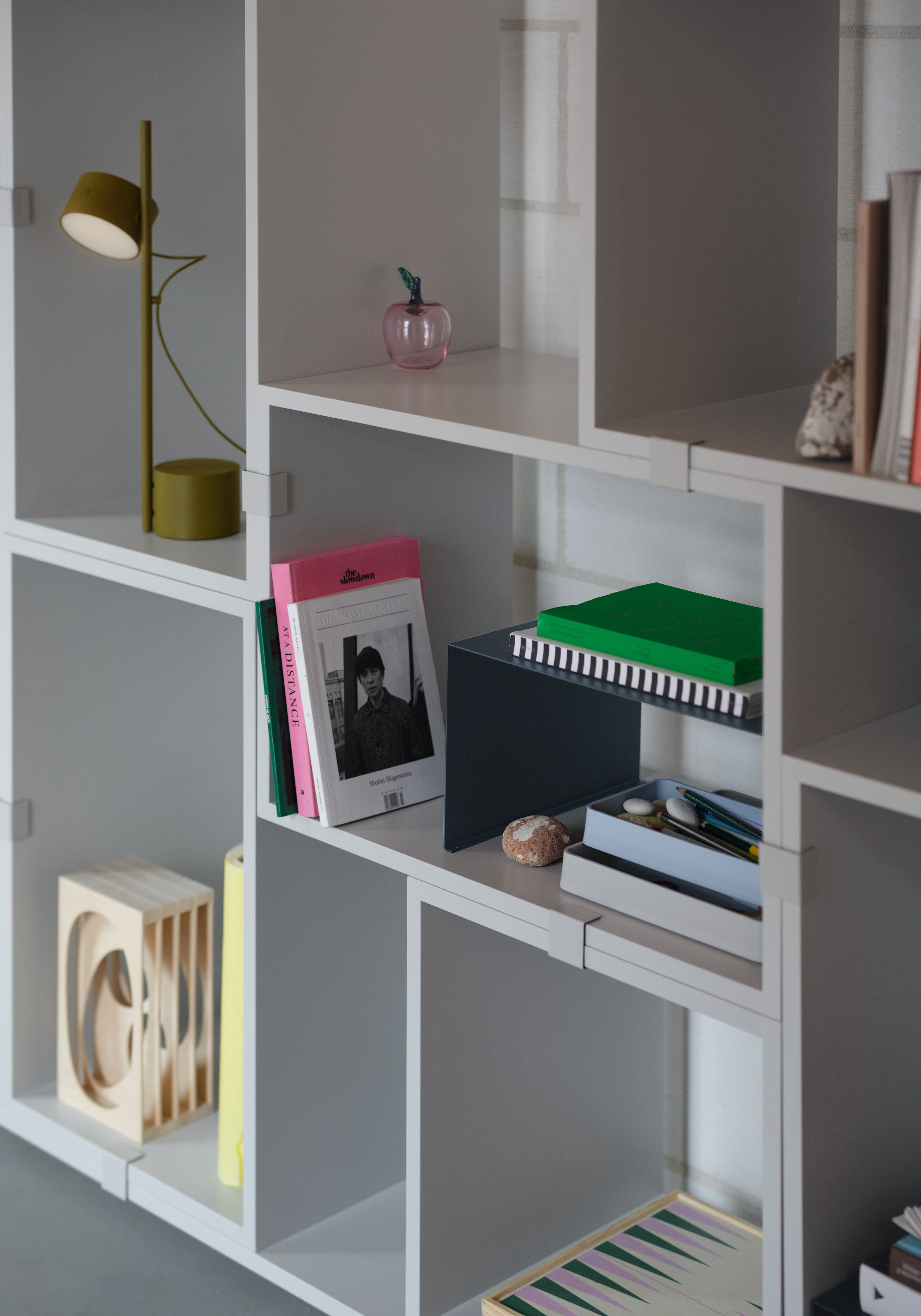 Interior setting featuring Stacked Bookcase in grey, paired with the Post Table Lamp in brown green.
