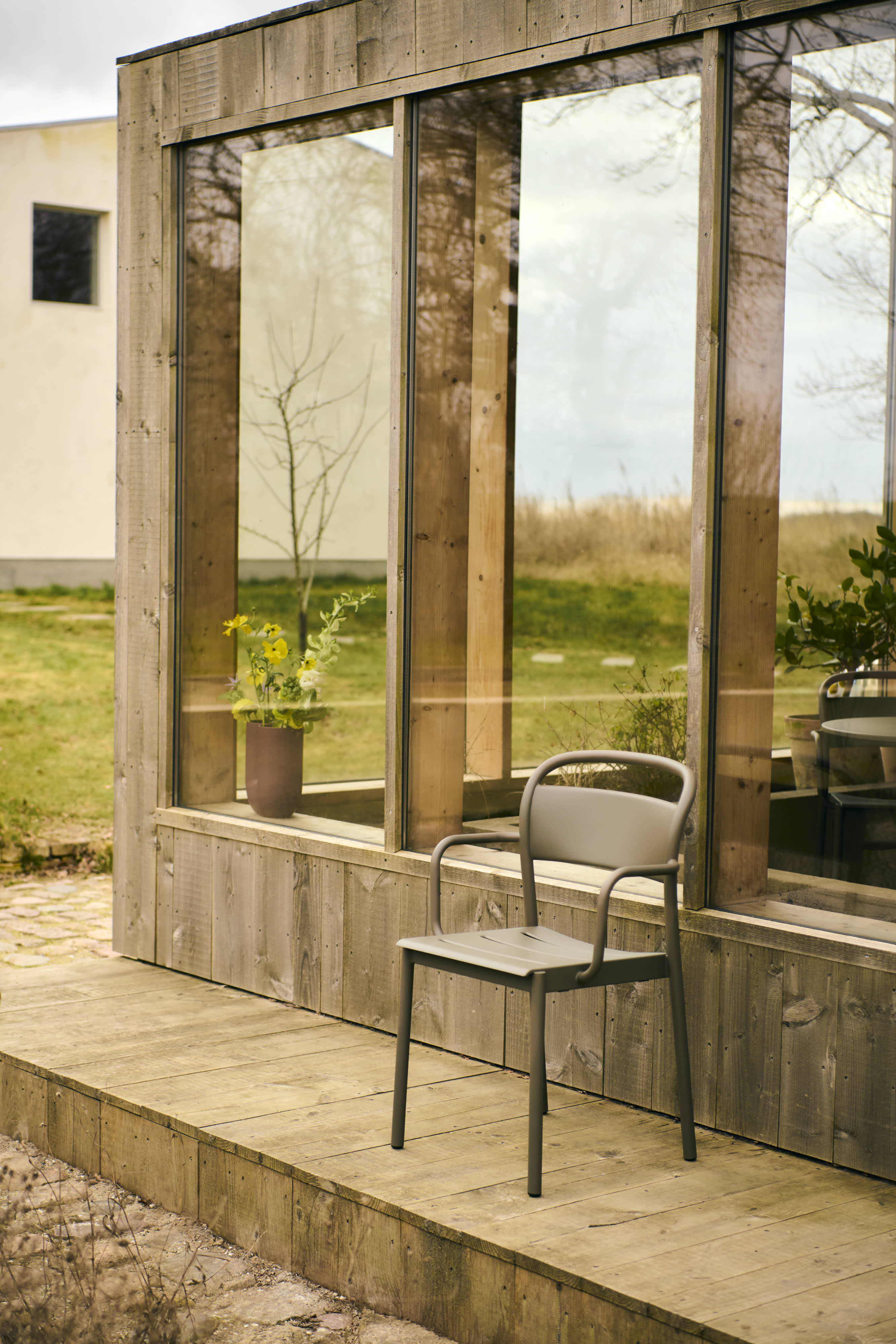 A modern outdoor armchair in a taupe color, positioned in an open outdoor setting for a relaxed, contemporary look.