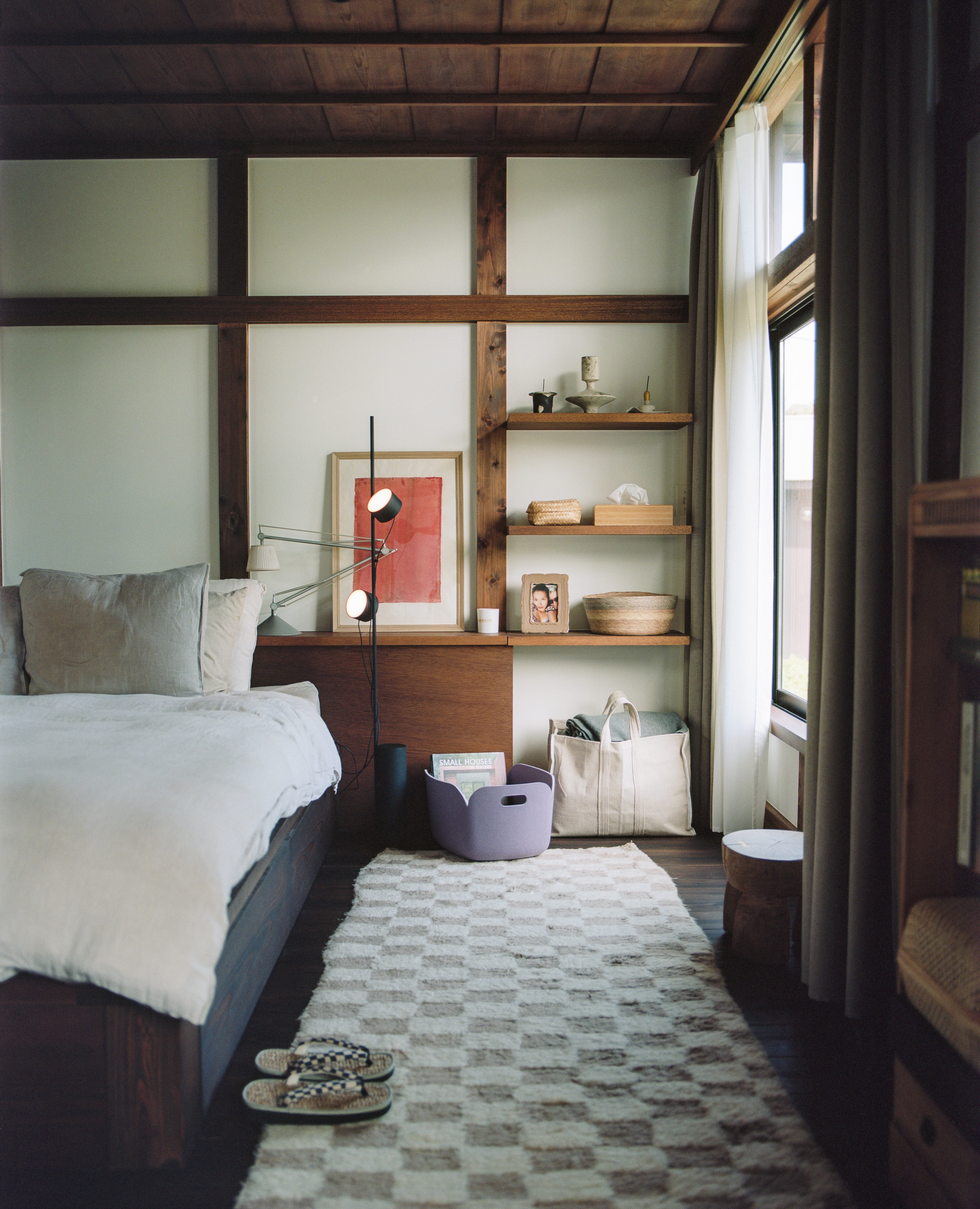 Minimalistic bedroom with wooden furniture, shelving, and a large area rug.