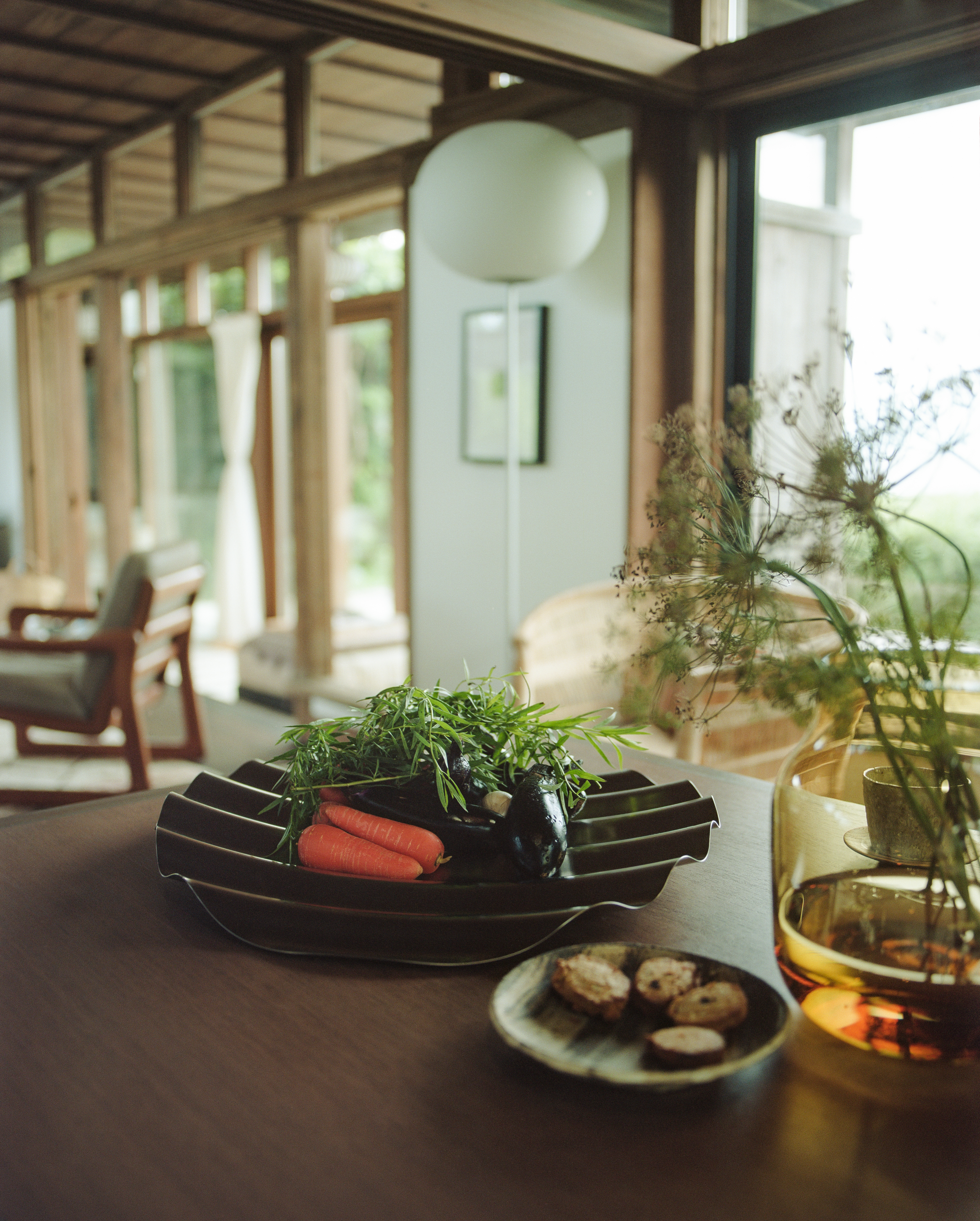 Dining table setup with Wave Tray containing vegetables and the Silent vase with flowers.