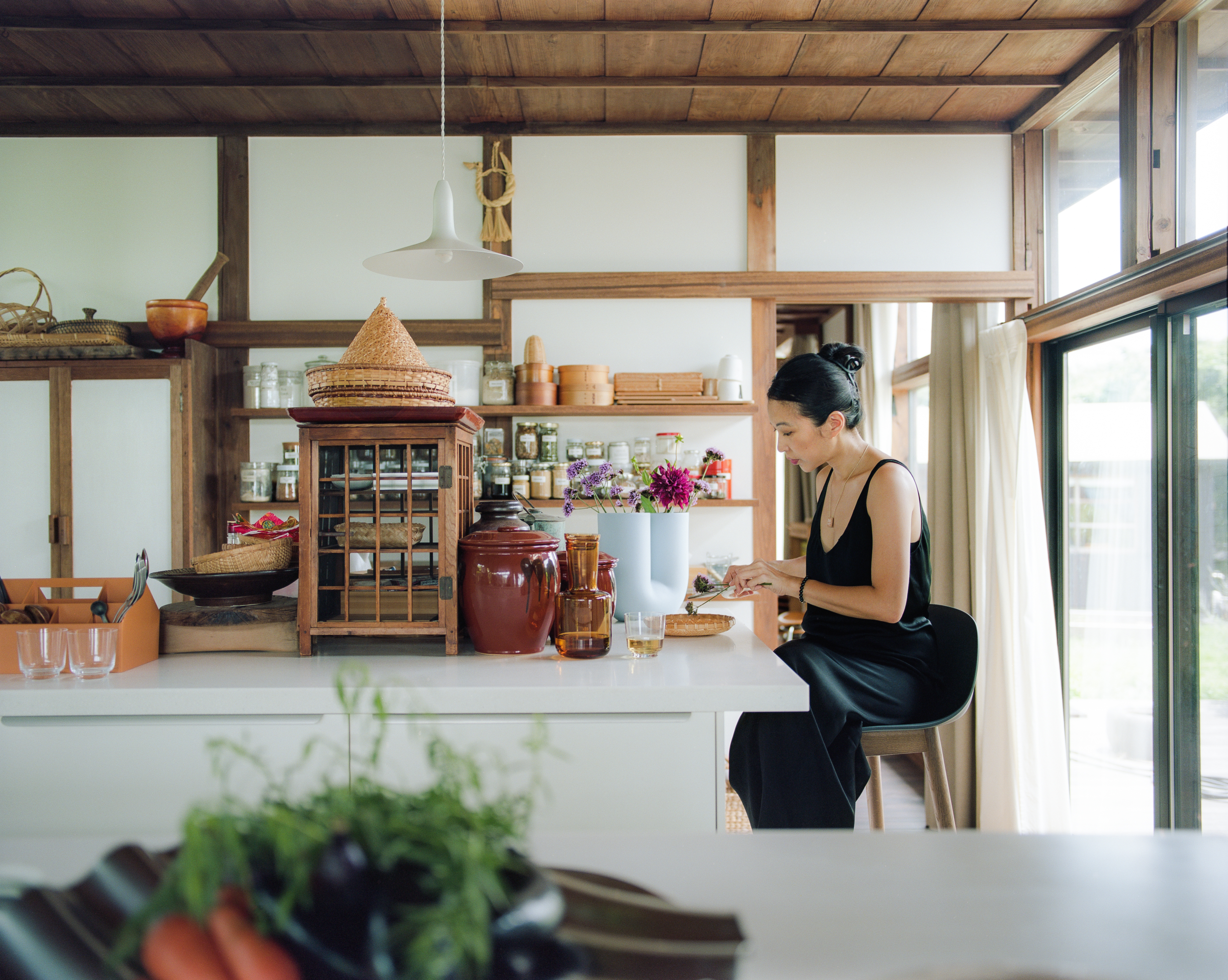 Giselle working in a spacious kitchen with wooden shelves.



