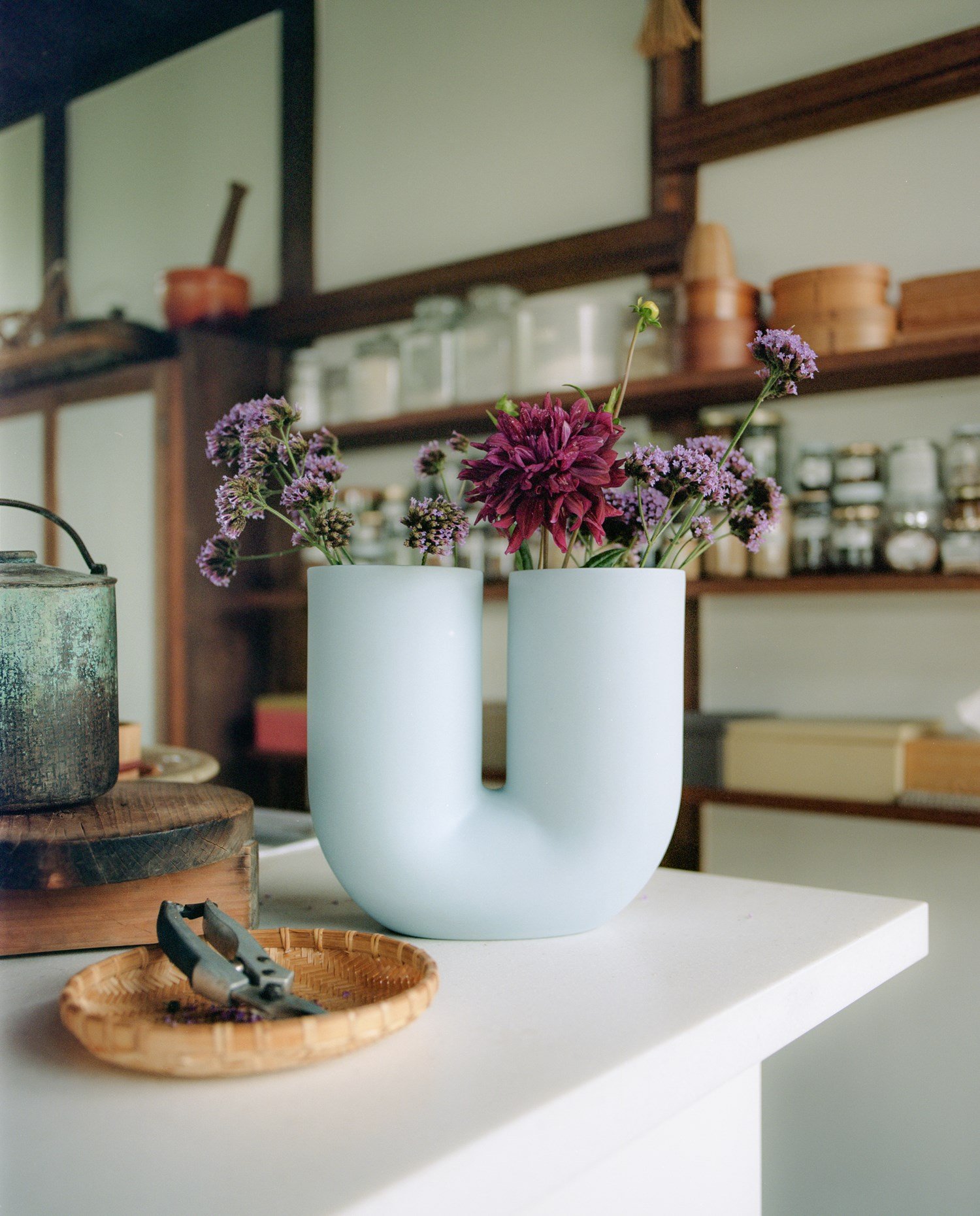 The Kink Vase in light blue with flowers on a kitchen counter. The Kink Vase in light blue with flowers on a kitchen counter.
