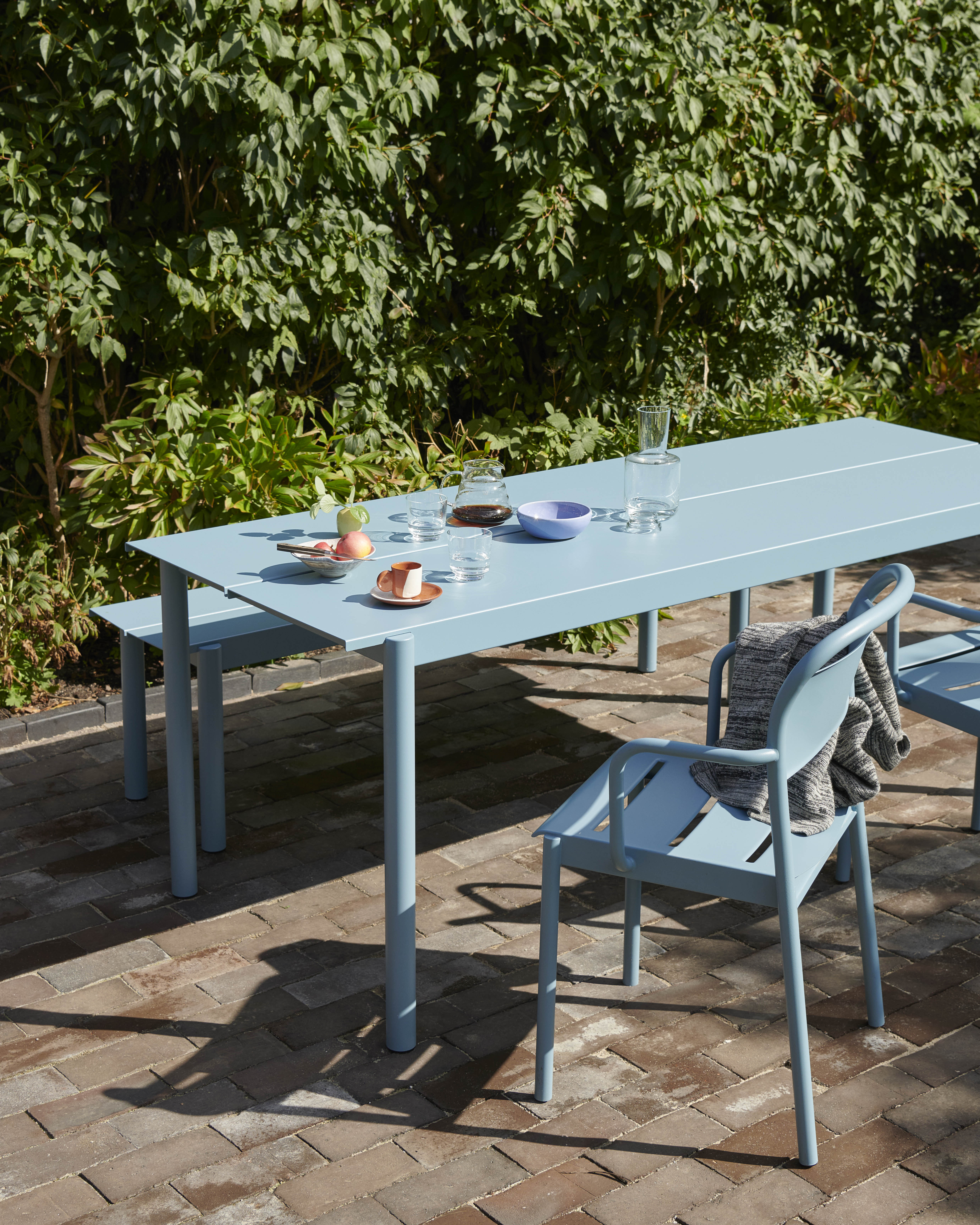 Outdoor setting with Linear Steel Table, chairs, and bench in a minimalist environment