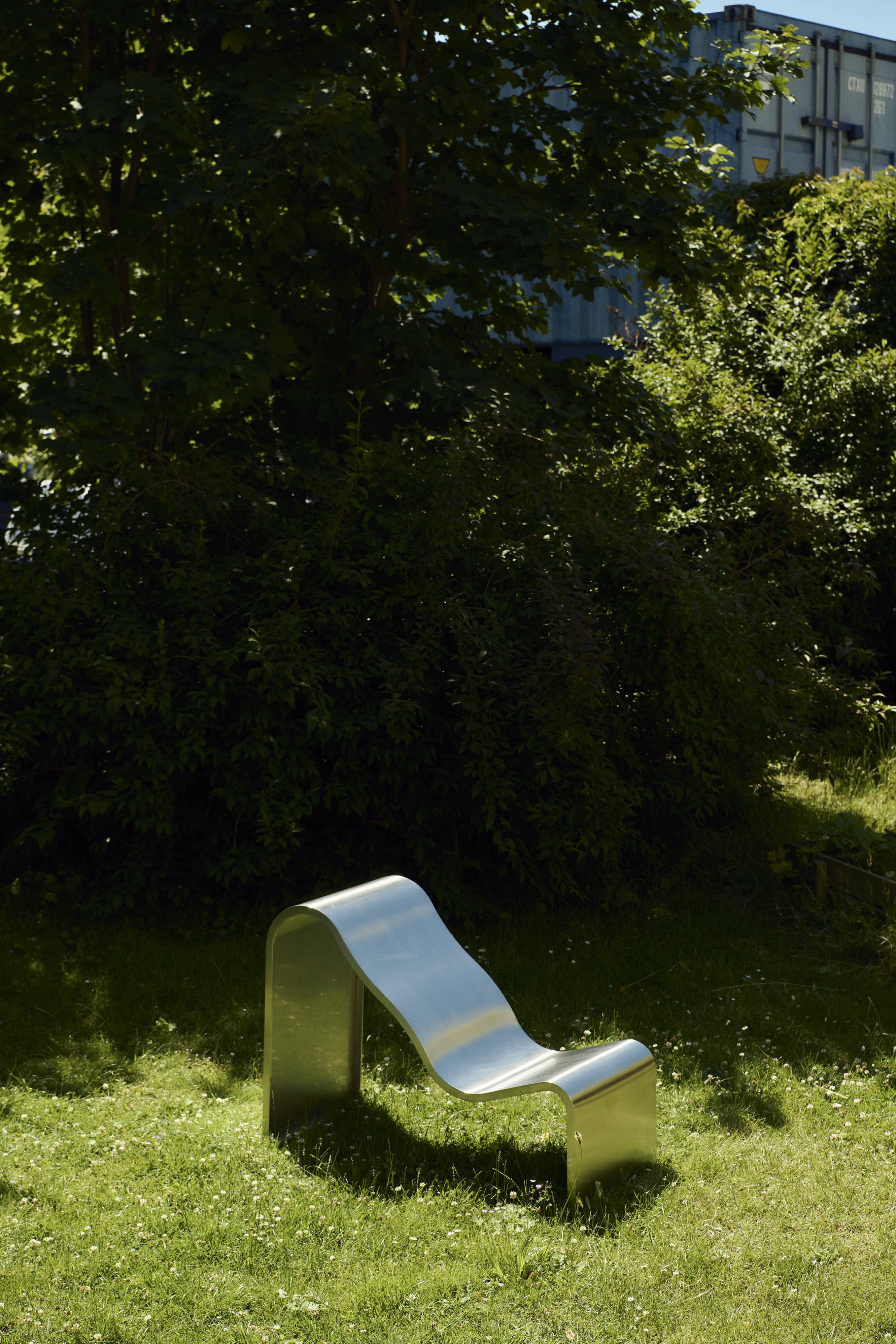 The Dream View Bench by Lise Vester placed on grass in an outdoor setting, highlighting its soft and organic form.