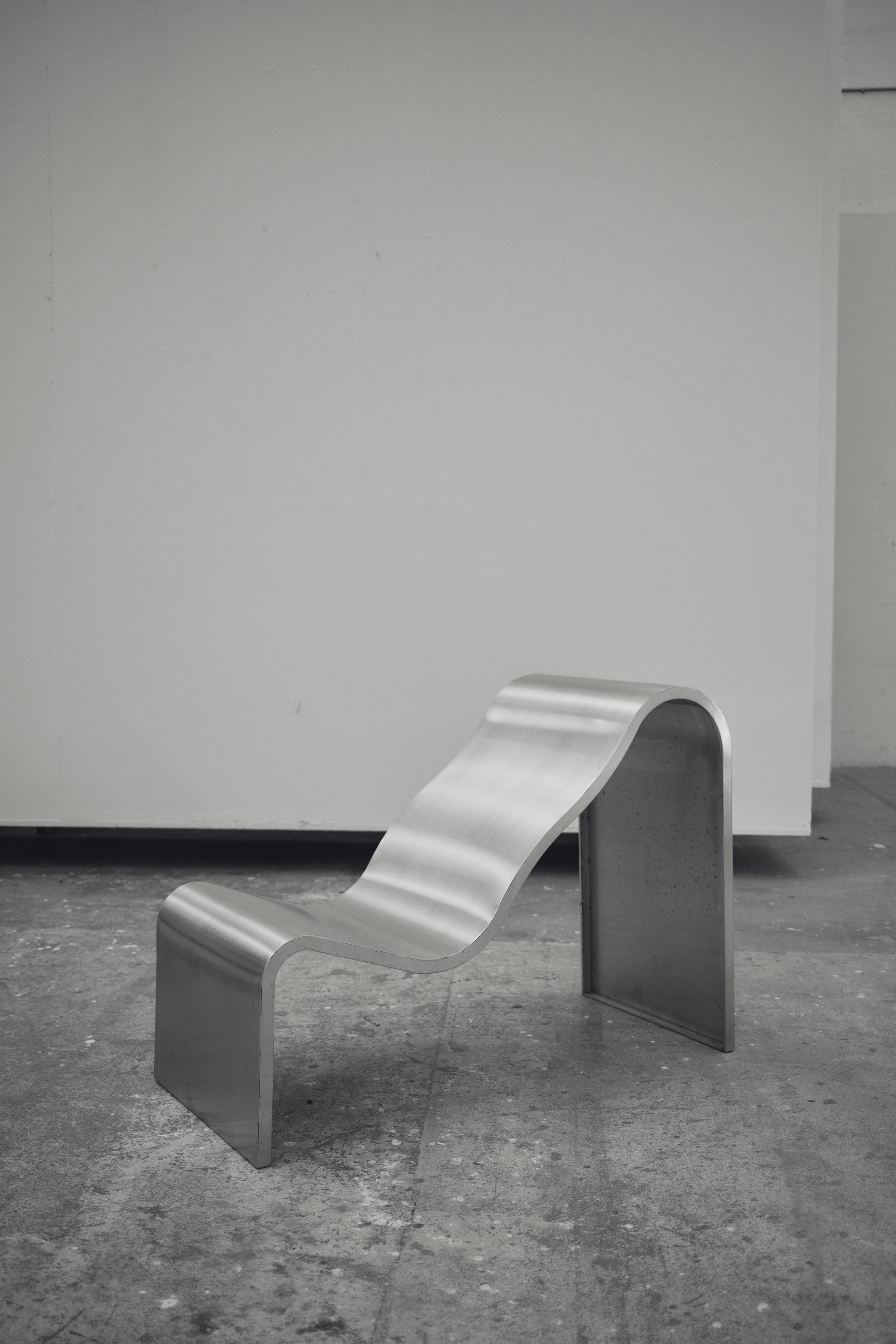 The Dream View Bench by Lise Vester placed in a raw, industrial setting, highlighting the contrast between its soft, organic form and the surrounding architecture.