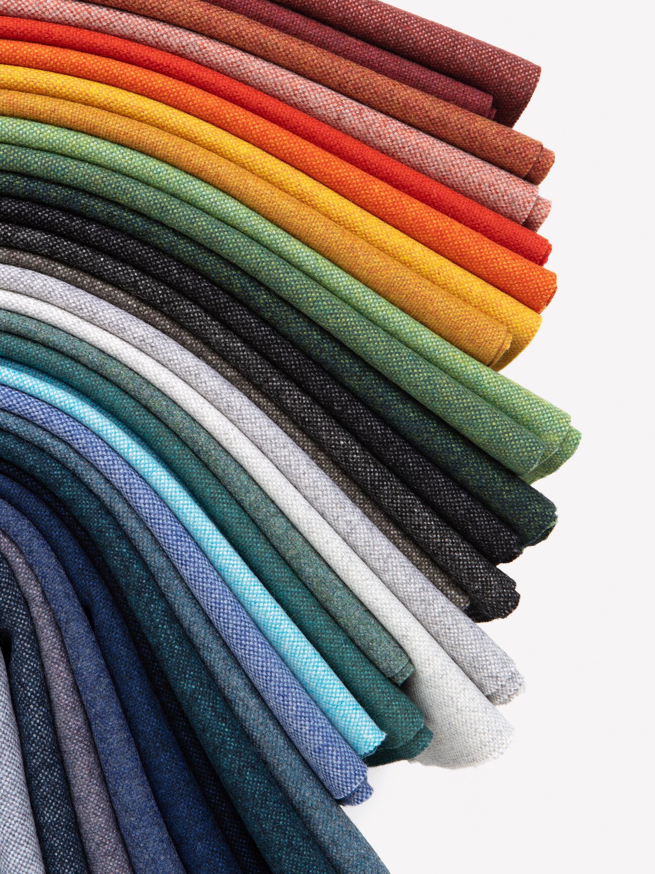Colorful rolls of fabric arranged vertically, displaying a spectrum of colors with detailed textures.