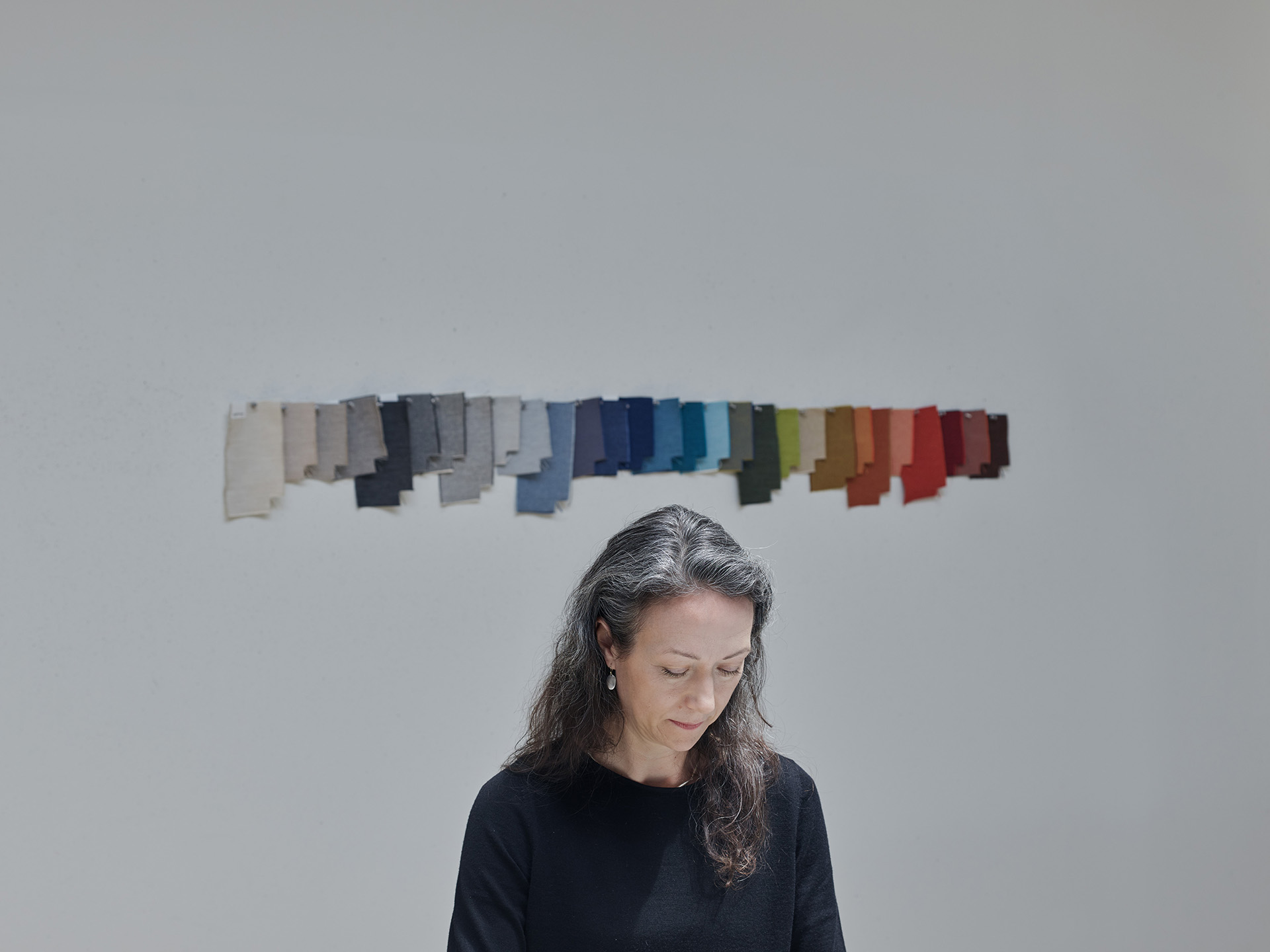 Sarah evaluating a linear array of color swatches in various hues, focused on her thoughtful expression.
