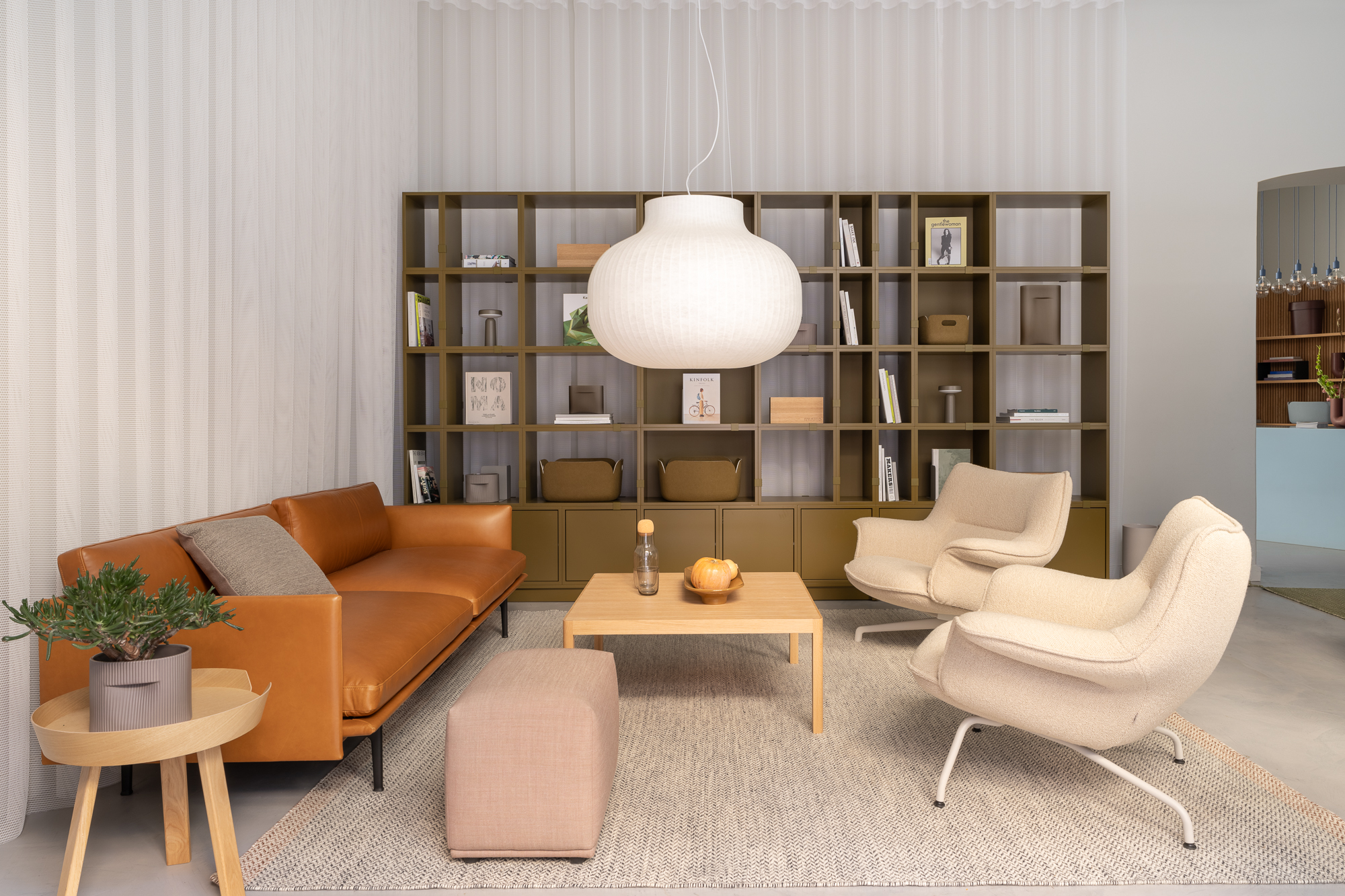 Cozy living room setup at Muuto's Stockholm flagship store. Neutral tones, contemporary lighting, and a chic vase centerpiece complete the setting.