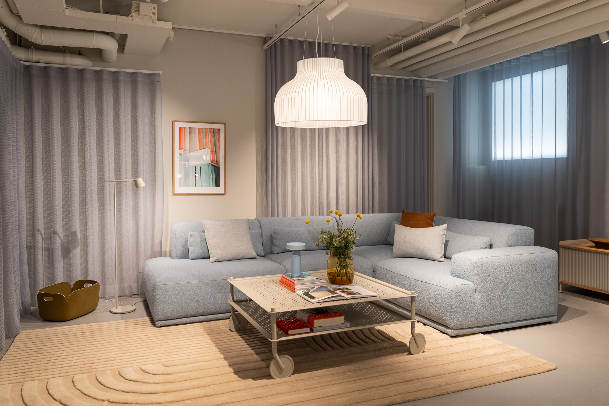 Cozy living room setup at Muuto's Stockholm flagship store. Soft pastel furniture, Scandinavian design, and warm ambient lighting create an inviting atmosphere.