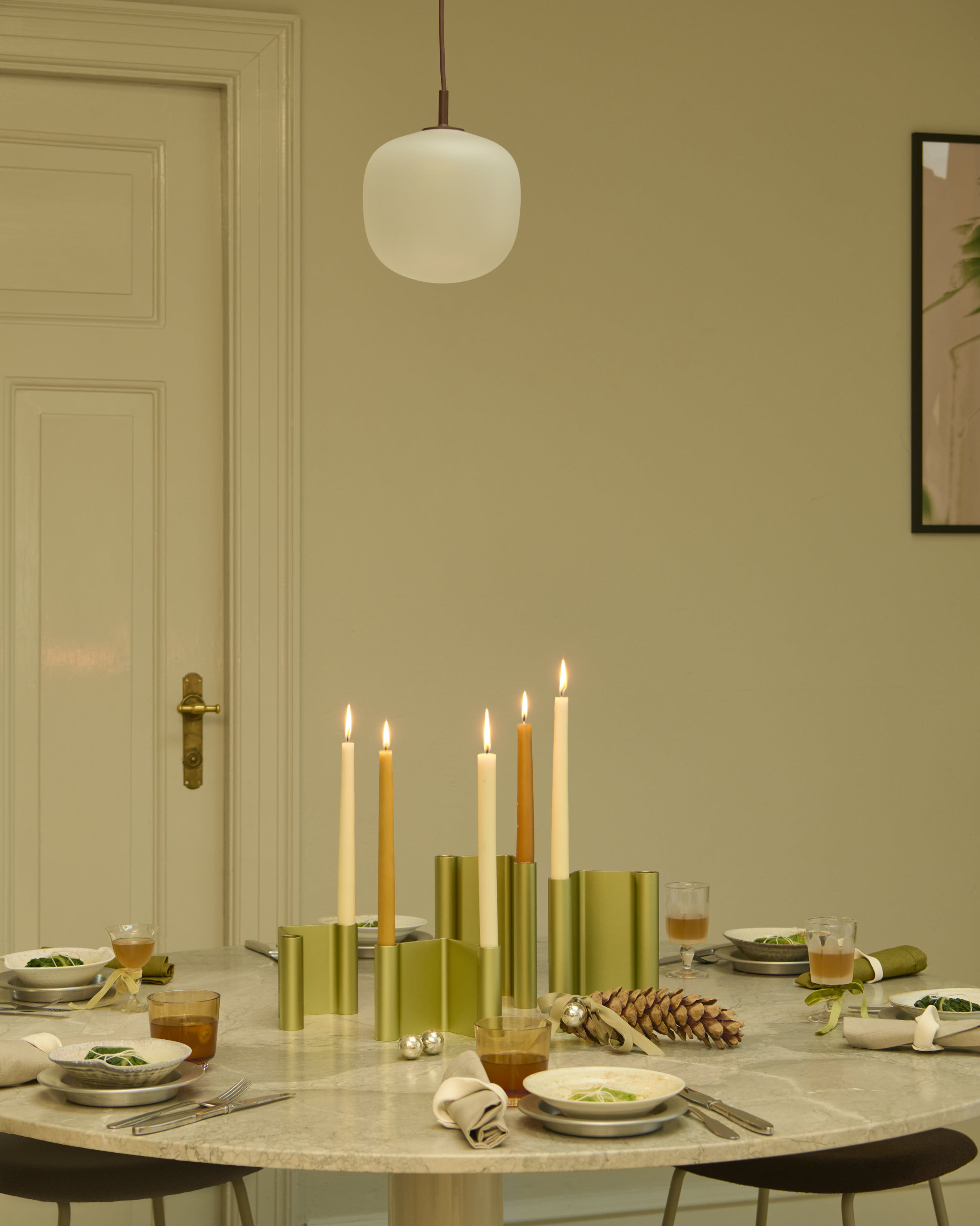 Holiday-themed interior featuring the Midst Table in grey marble, styled with the Pair Candleholder in green, Raise Glass, Rime Pendant Lamp, and the Fiber Stool upholstered in Acca 381. A warm and refined setting with seasonal details.